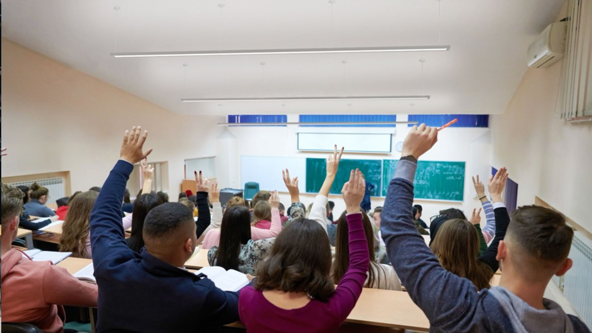An occupied lecture hall illuminated by Proper suspended linear fixtures.